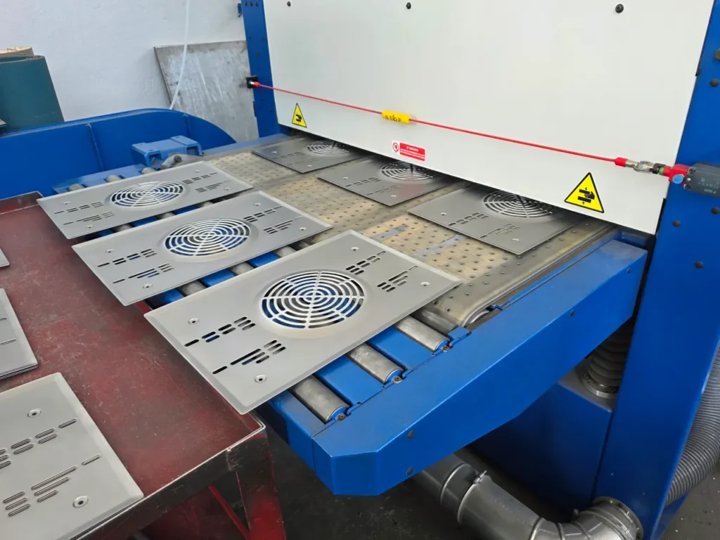 Centro di satinatura automatico in funzione su carter in acciaio inox